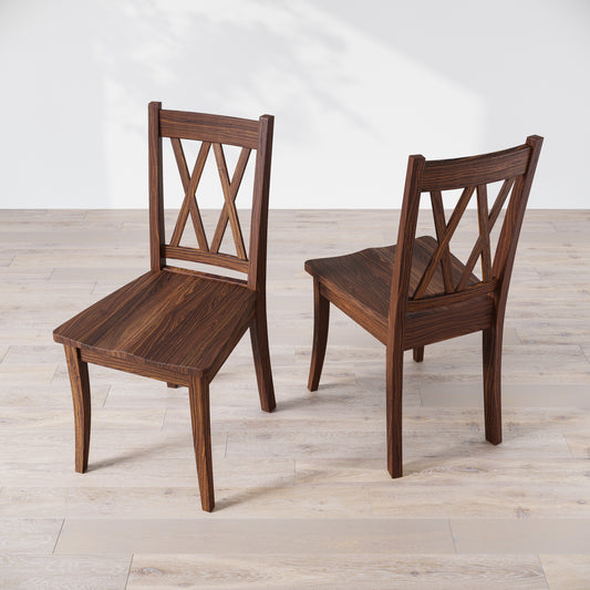 Top down view of two wooden dining chairs with a 'Double X Back' design, placed against a neutral background.