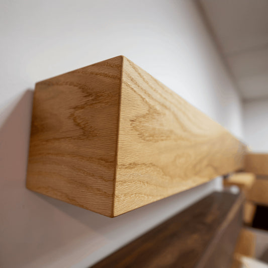 A brown oak wood mantel shelf attached to a wall, showcasing the natural grain of the wood.