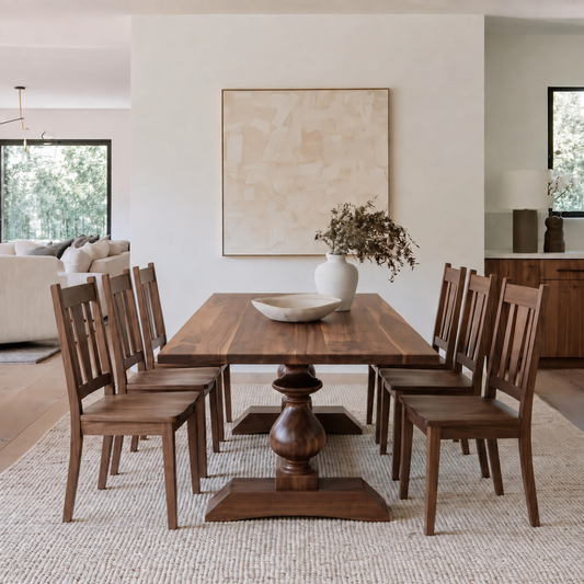 A dark brown wooden dining table with matching slat-back chairs, styled in a bright, modern dining room with a neutral abstract painting on the wall.