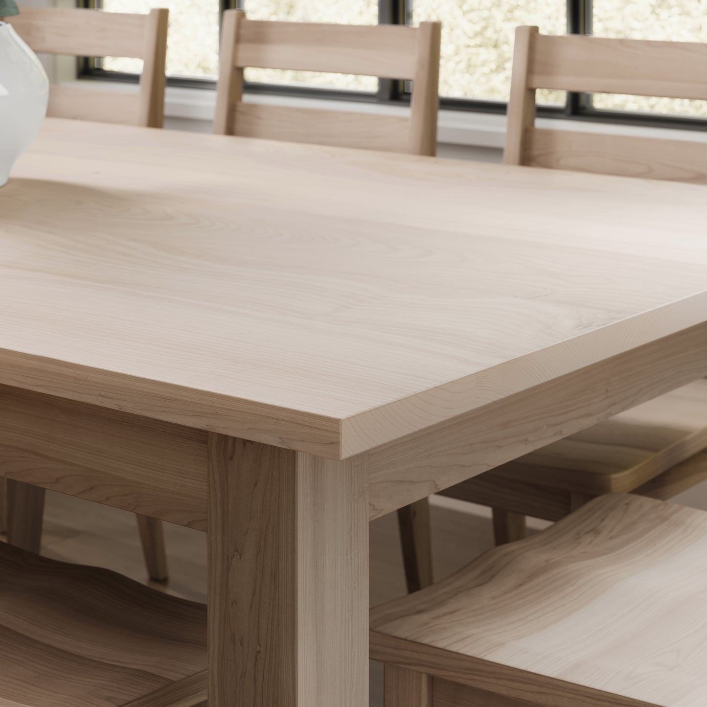 Close up corner view of a maple parson style dining table in a brightly lit dining room