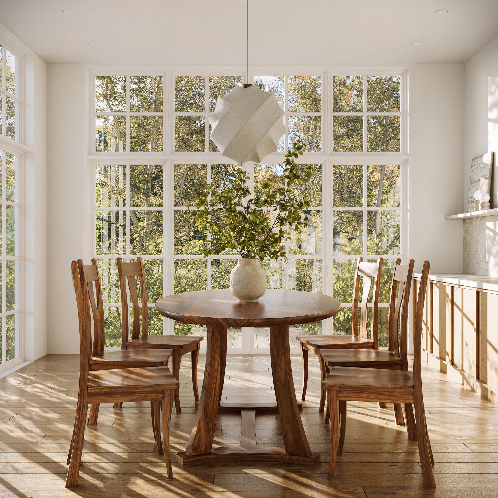 An oval dining table made of wood, with four matching chairs, placed in a room with large windows and wooden flooring.