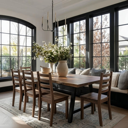 Dining room with wooden table and chairs, large windows, and a chandelier.