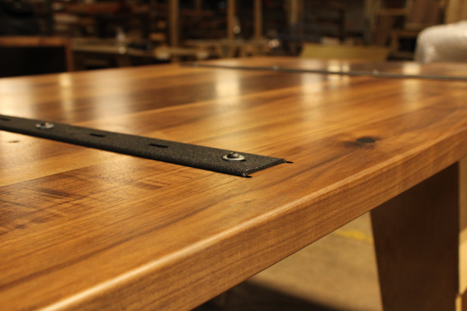 Close-up of a wooden table with metal brackets in a workshop setting