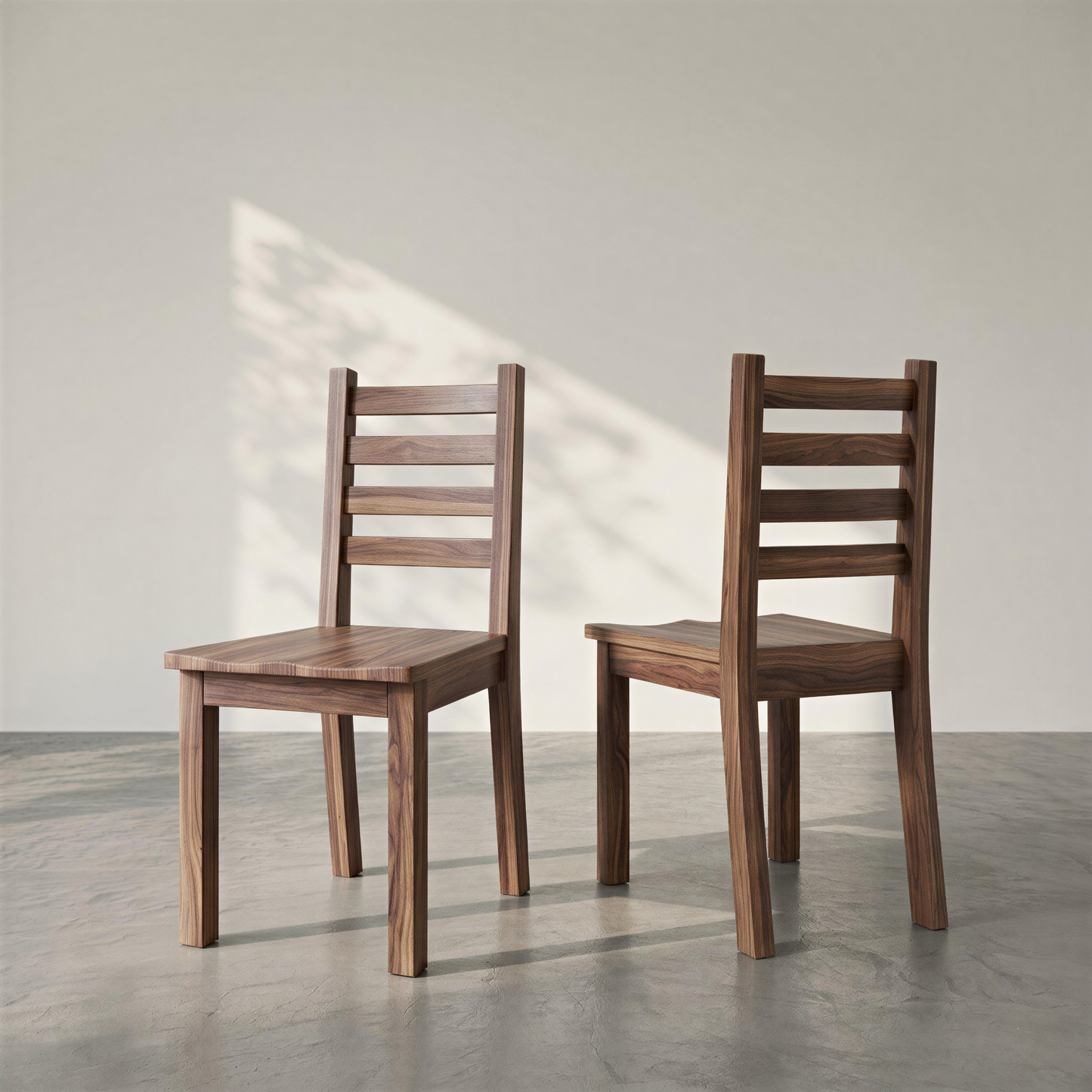 Two wooden chairs on a concrete floor with a light gray wall background