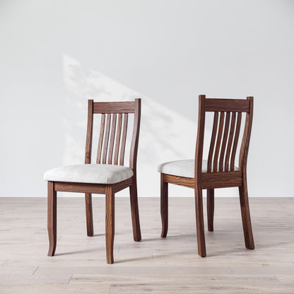 Two brown wooden dining chairs with upholstered seats, one facing forward and the other showing the side profile.