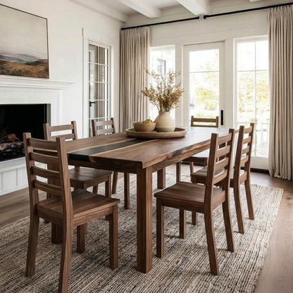 A rustic wooden dining table with six matching ladder-back chairs, styled in a bright, modern dining room with a fireplace and large windows.