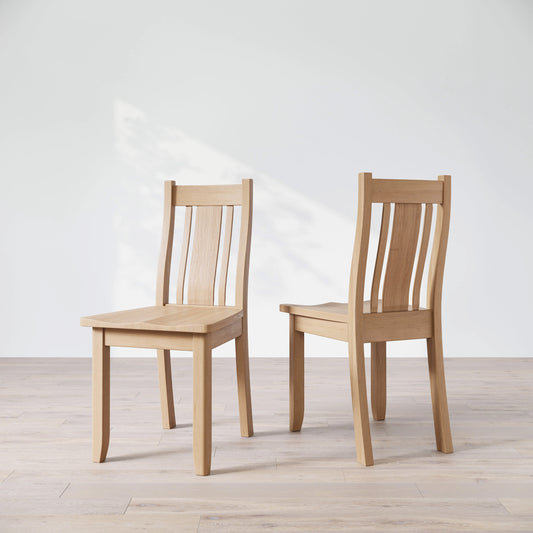 Two wooden chairs on a light wooden floor with a white background