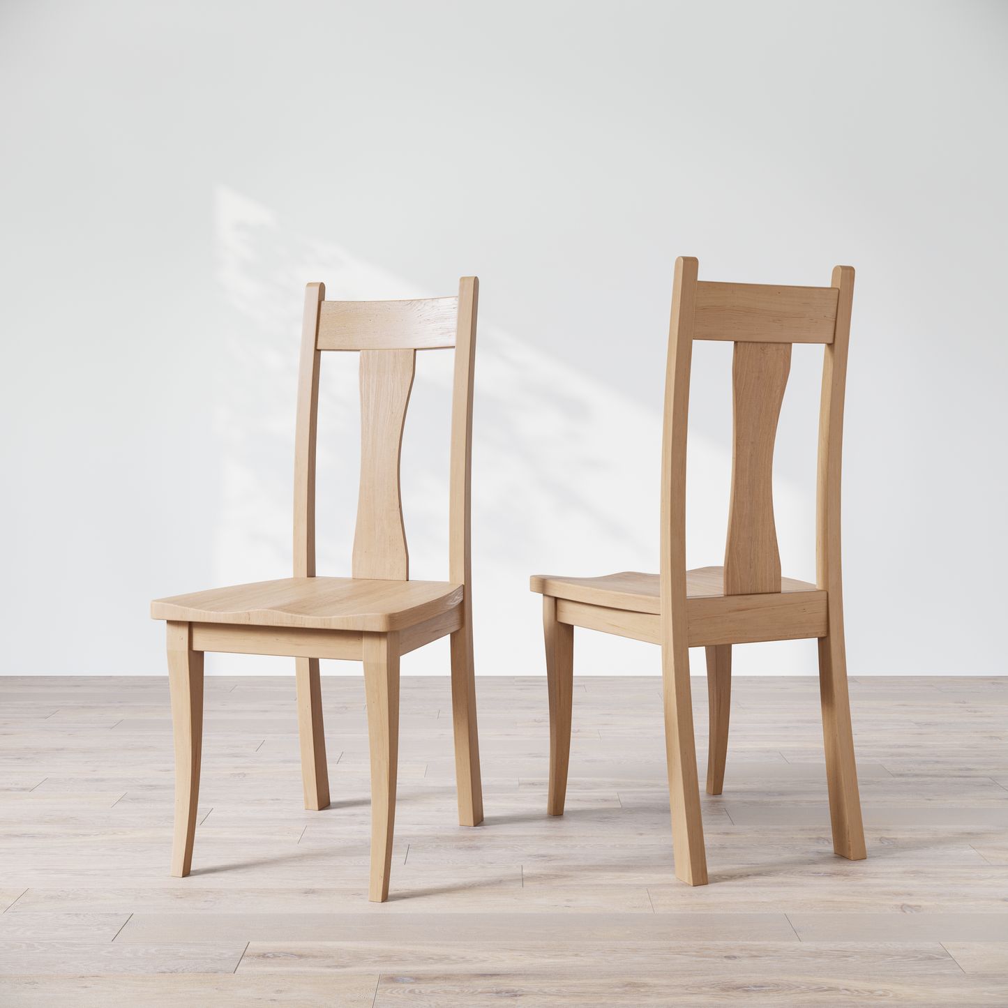 Two maple wooden dining chairs with, one in front of the other, against a white background.