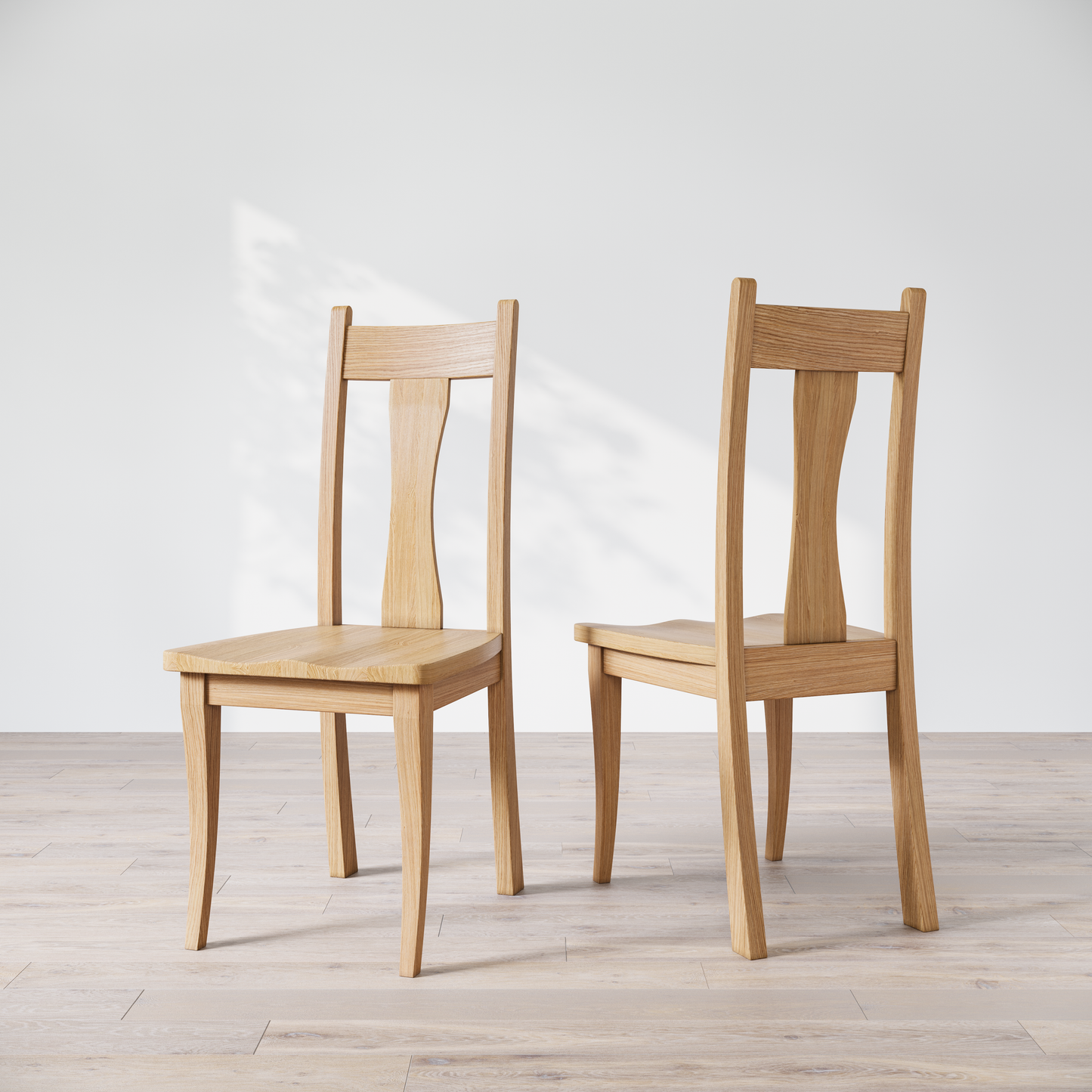 Two oak wooden dining chairs with, one in front of the other, against a white background.