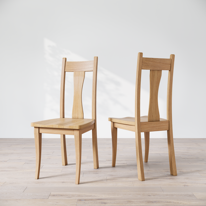 Two oak wooden dining chairs with, one in front of the other, against a white background.