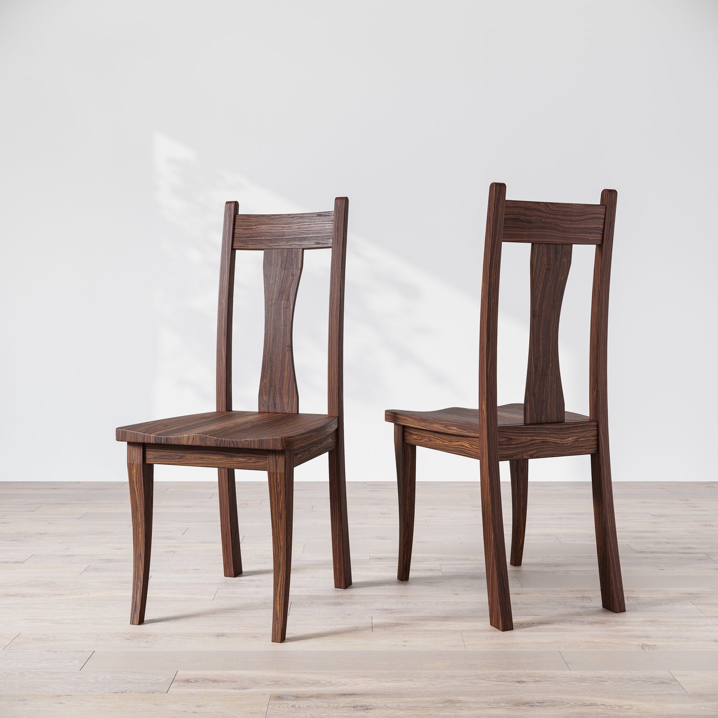 Two walnut wooden dining chairs with, one in front of the other, against a white background.