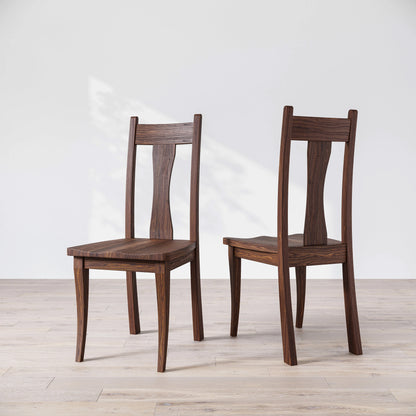Two wooden chairs on a light wooden floor with a white background