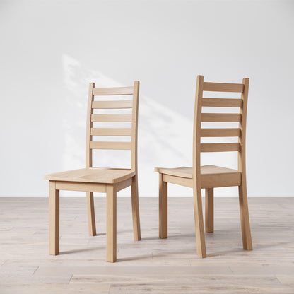 Two wooden dining chairs with a commercial grade finish, displayed against a white background.