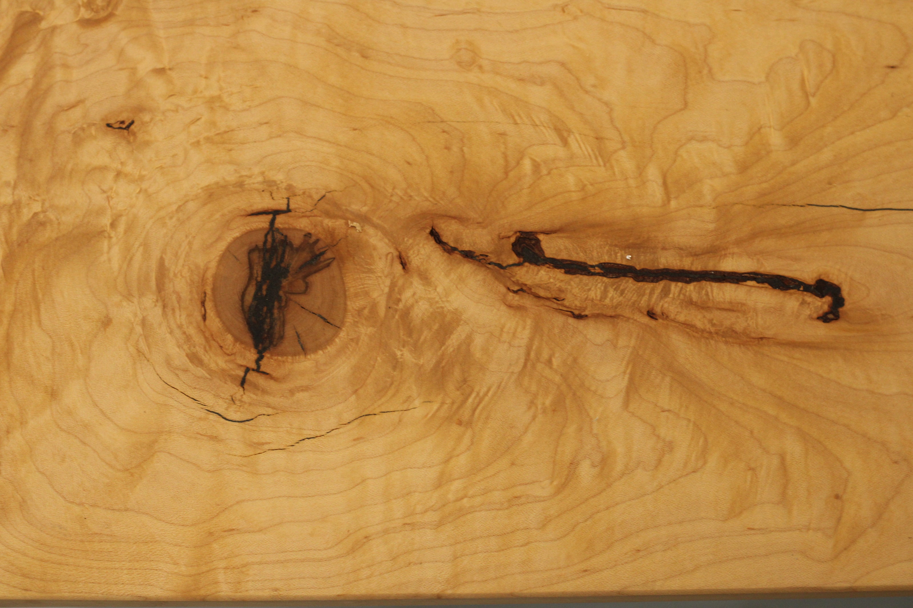 Close-up of a wooden surface with a large knot and visible grain patterns.