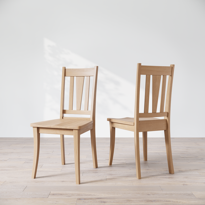 Two maple dining chairs with a brown finish, showcasing a slatted backrest and a solid seat, placed against a white background.