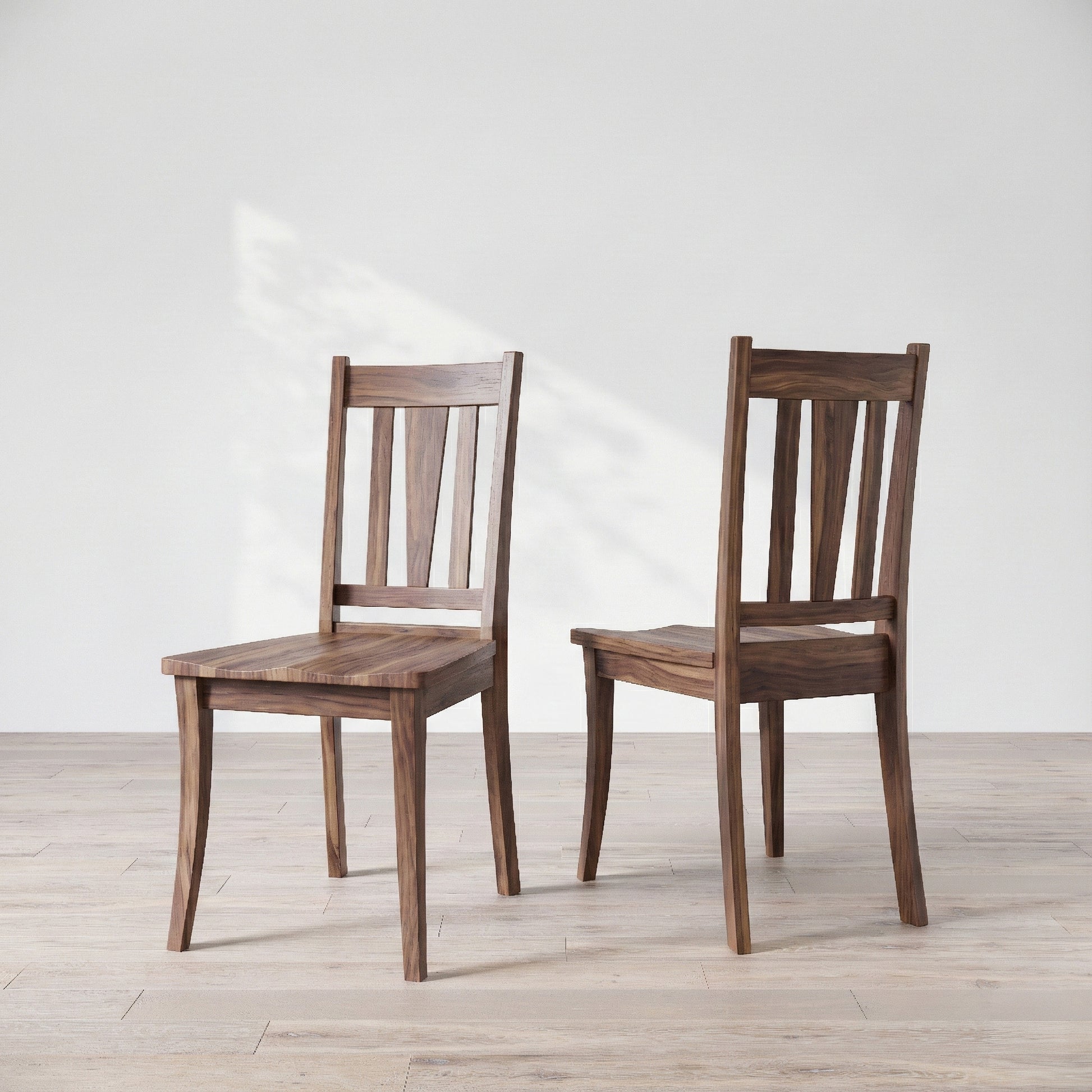 Two wooden chairs on a light wooden floor with a white background
