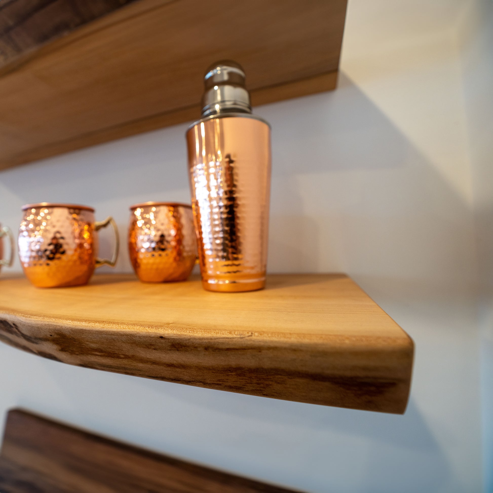 Two live edge maple shelves mounted on a wall, with decorative items and plants displayed on them.