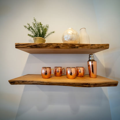 Two live edge maple shelves mounted on a wall, with decorative items and plants displayed on them.
