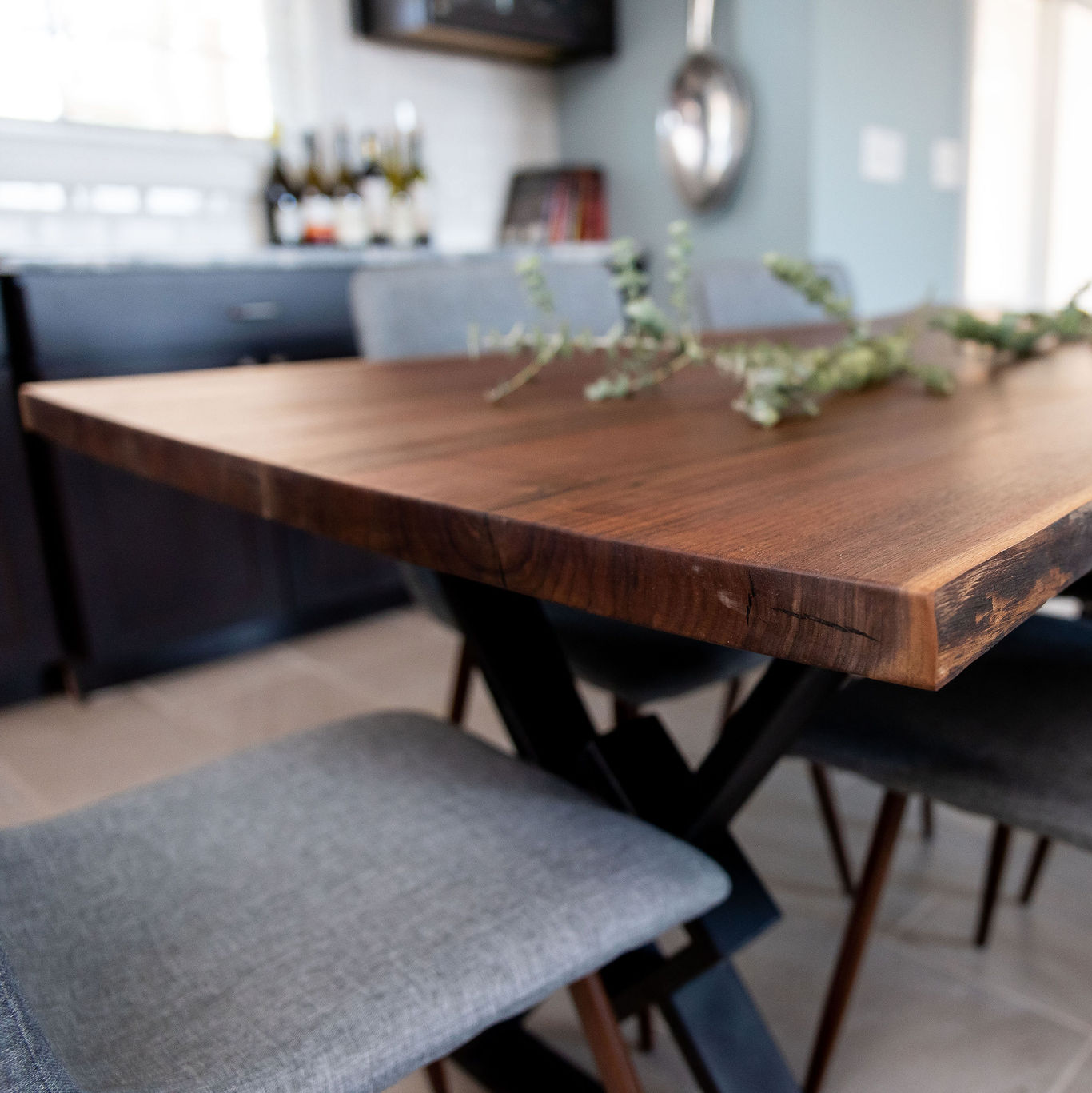 Live Edge black walnut dining table in a small dining room with grey upholstered chairs on either side