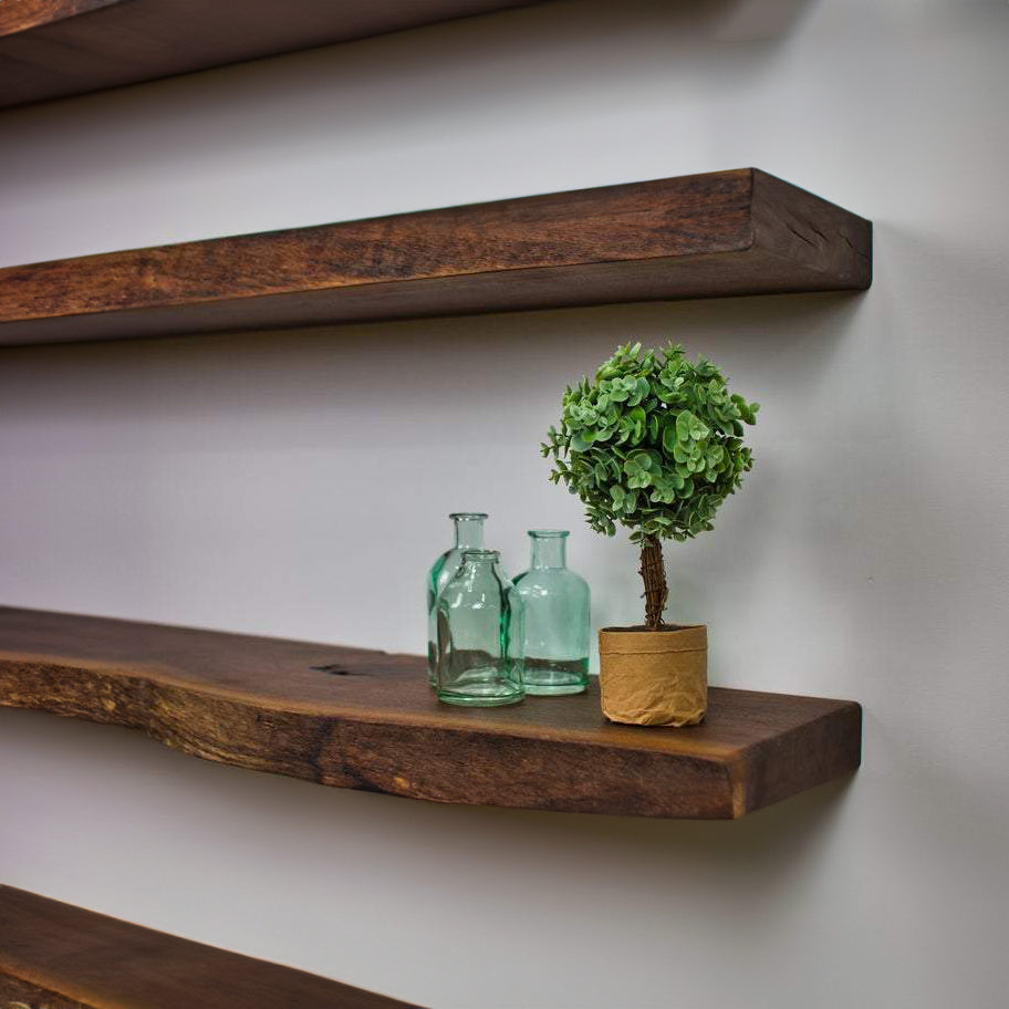 Close up showing the ends of a handful of live edge walnut floating shelves mounted to a white wall