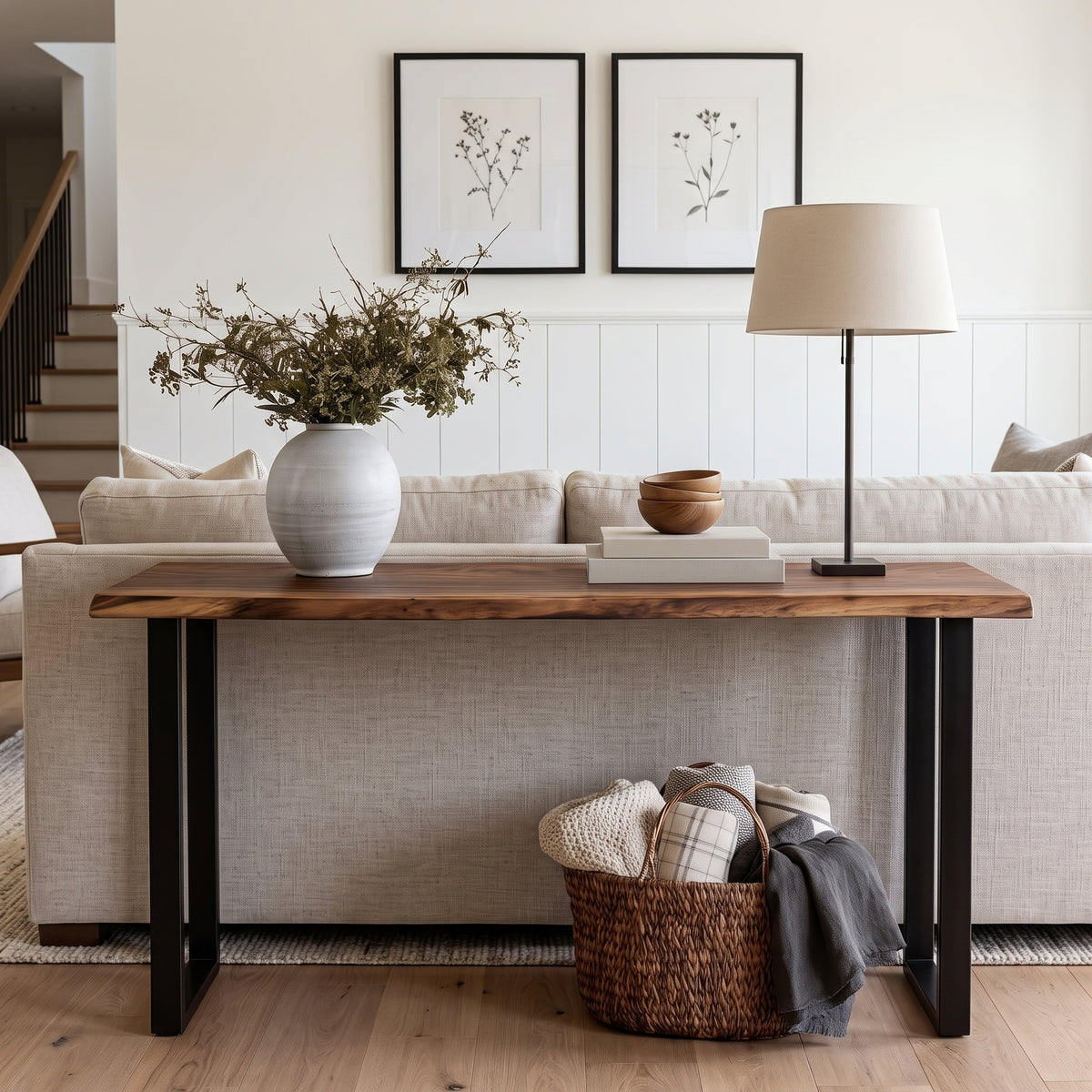 A rustic farmhouse-style console table with a live-edge medium brown wood top and black metal legs, styled in a bright living room setting.