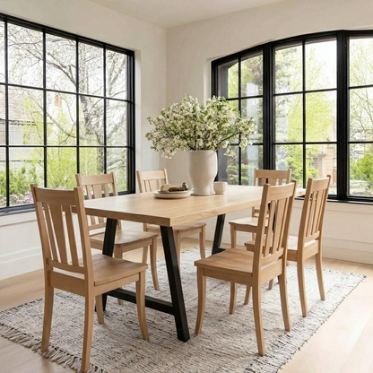 Dining room with wooden table and chairs, large windows, and a vase of flowers.