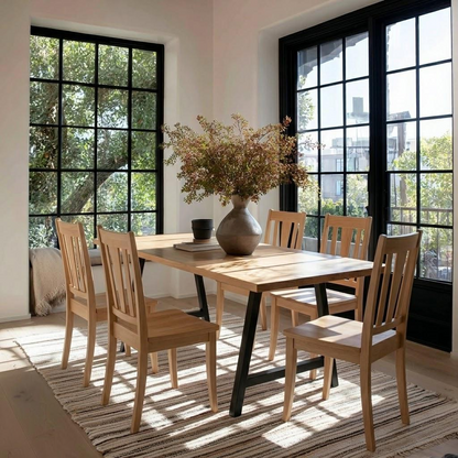 Dining room with wooden table and chairs near large windows.