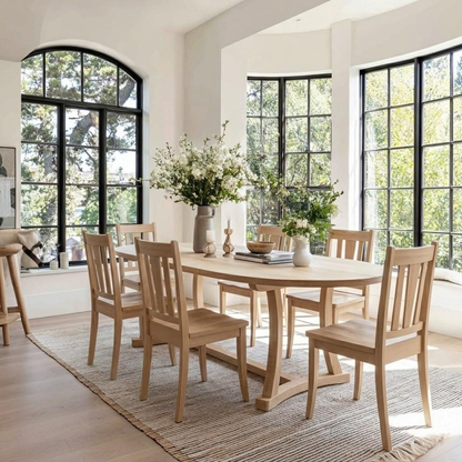 Dining room with wooden table and chairs near large windows.