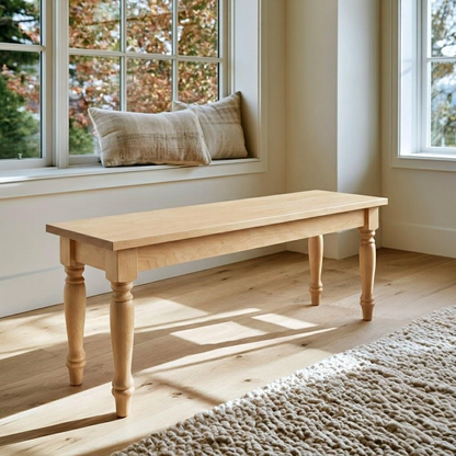 A light natural wood bench with turned legs, positioned in a bright room next to a window with a beige cushion on the sill.