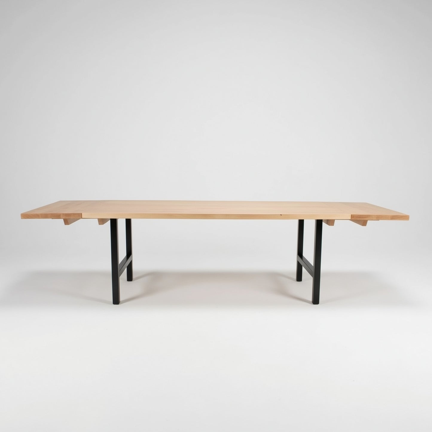 Wooden table with end extensions with black legs on a white background