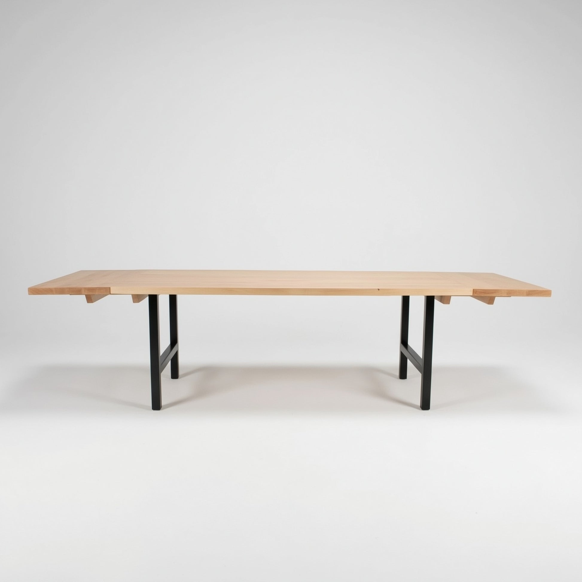 Wooden table with end extensions with black legs on a white background