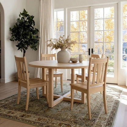 Dining room with wooden table and chairs, vase with flowers, and large windows.