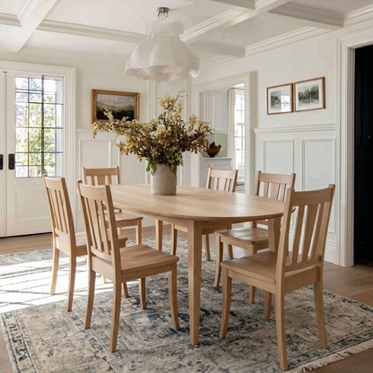 Dining room with wooden table and chairs, vase of flowers, and framed pictures on the wall.