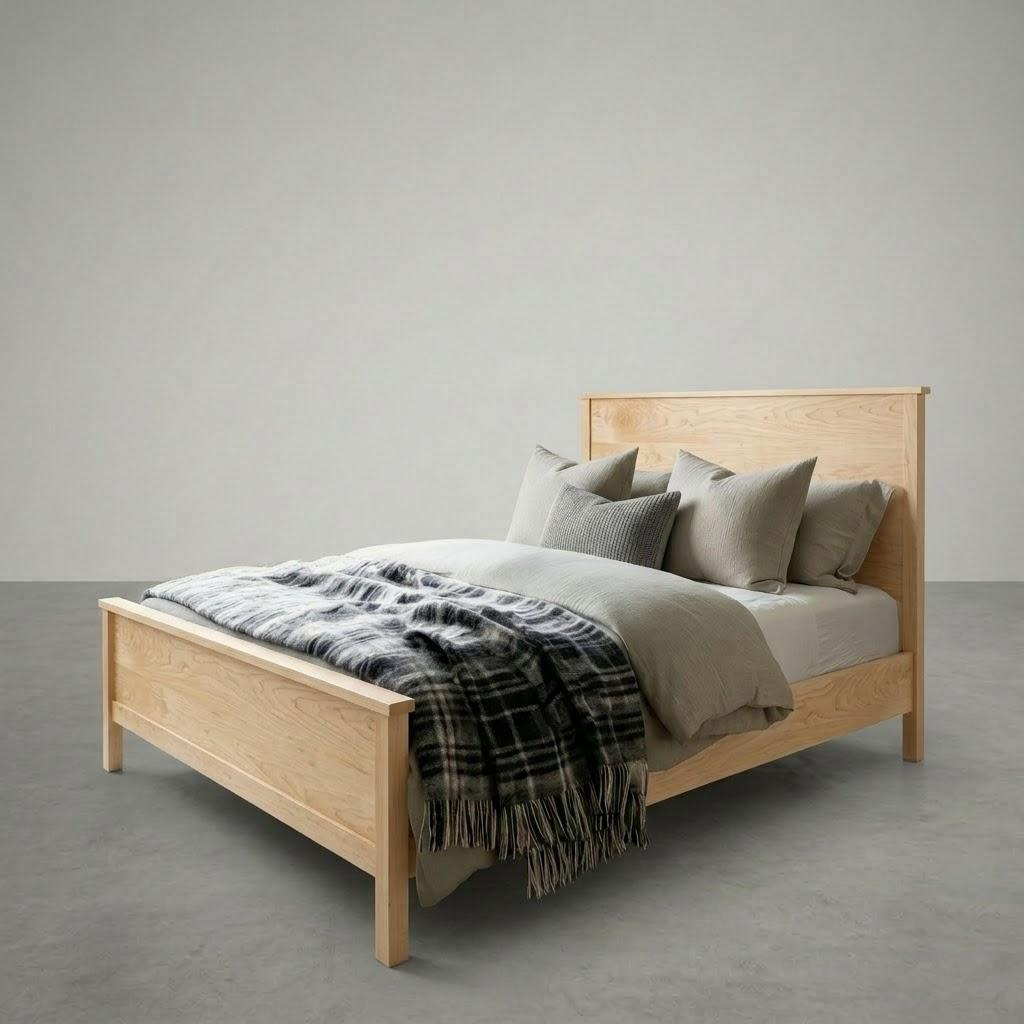Wooden bed with bedding and a plaid blanket against a plain background