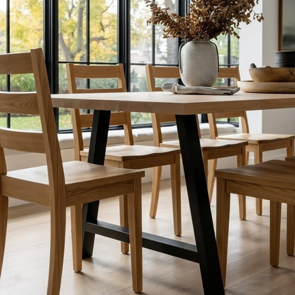 Dining table with wooden chairs in a room with large windows.