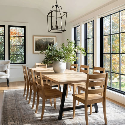 Dining room with wooden table and chairs, large windows, and a rug.