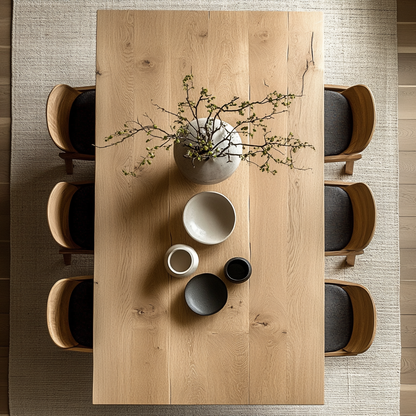 A well-appointed dining room featuring a large rectangular dining table with a wood finish, surrounded by light-colored chairs with metal legs. The room has a modern aesthetic with a straight-line design and a minimalist decor style.