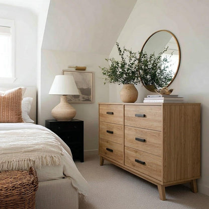 Neatly arranged bedroom with wooden dresser, round mirror, and bed.
