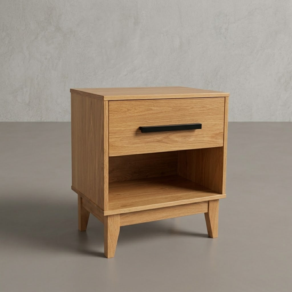 An Oak Astoria Nightstand with a single drawer featuring a black metal bar handle and an open lower shelf, set against a textured gray wall and floor.