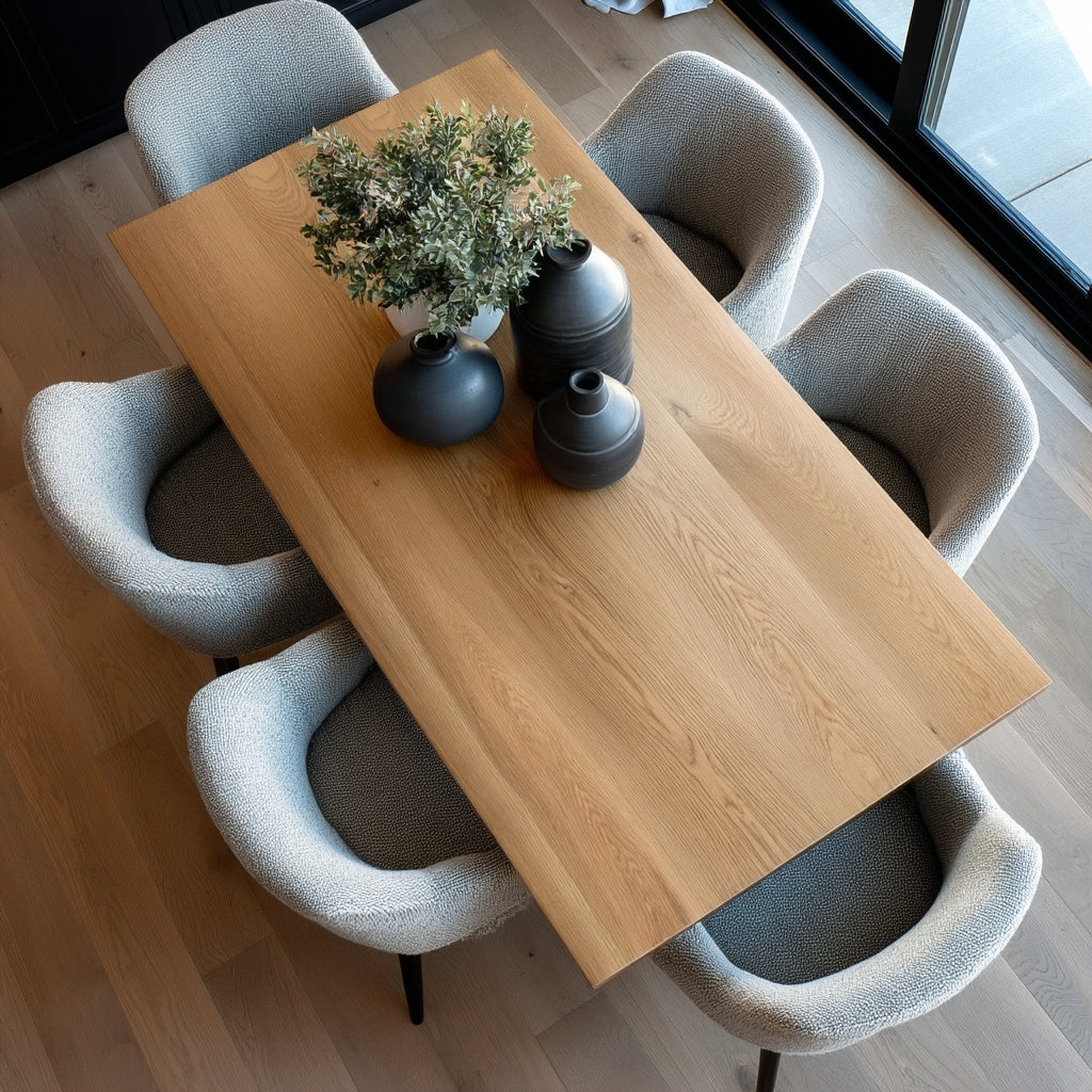 Dining table with decorative vases and a plant, surrounded by modern chairs in a well-lit room.