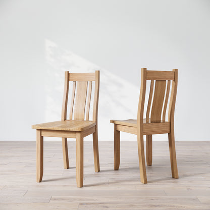 Two oak wood Finley dining chairs with a natural finish, showcasing a straight back and seat design on a light background.