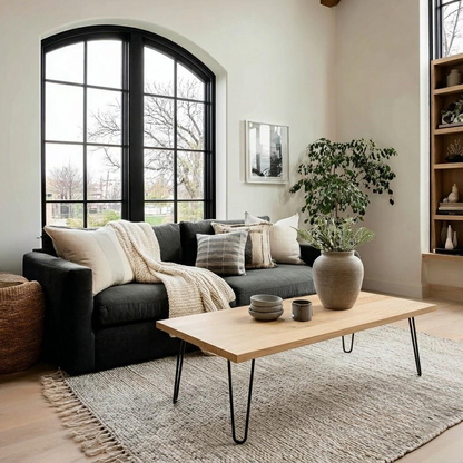 Modern living room with a gray sofa, wooden coffee table, and large windows.