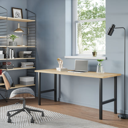 A sleek modern desk with a wooden top and black metal legs, situated in a well-lit room with a chair pulled up to it. Decorative items and a framed picture hang on the wall in the background.
