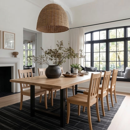 Dining room with wooden table and chairs, large windows, and a wicker pendant light.