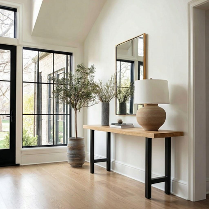 Modern interior with a wooden console table, lamp, and decorative items against a white wall.
