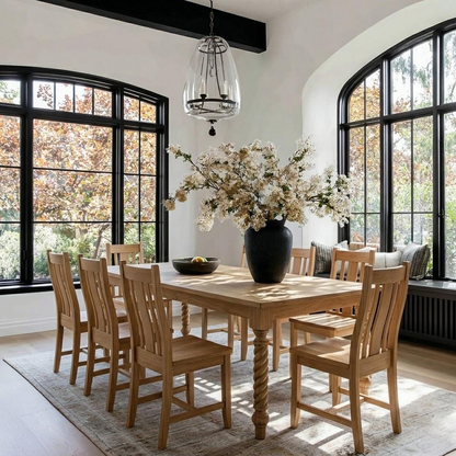 Dining room with wooden table and chairs near large windows.