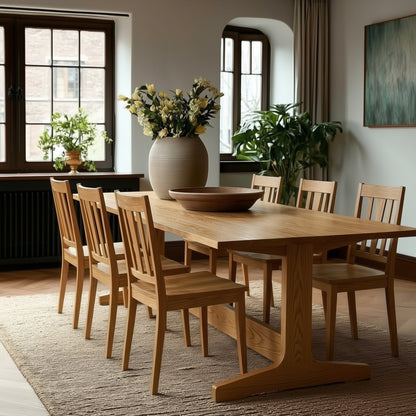 Dining room with wooden table and chairs, vase with flowers, and plants.