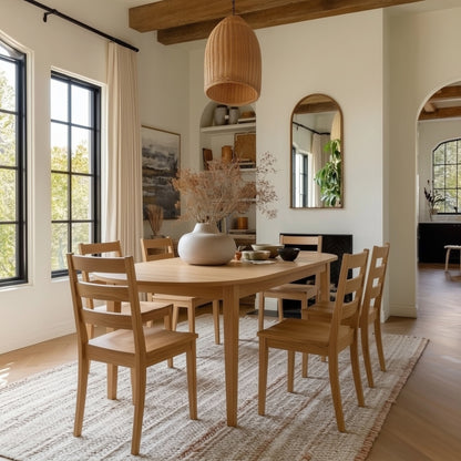 Dining room with wooden table and chairs, large windows, and a rug.