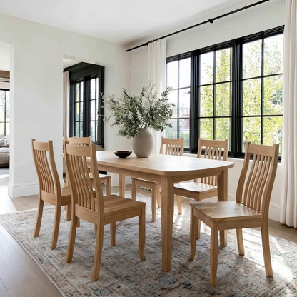 Dining room with wooden table and chairs in a bright room with large windows.