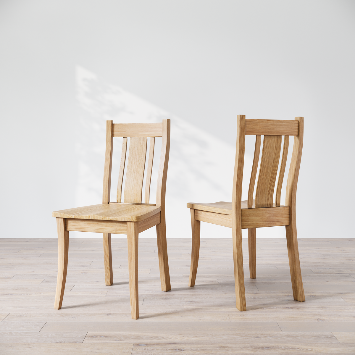 Two oak Shapleigh solid wood dining chairs in a studio setting